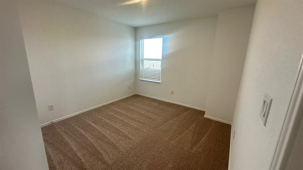 192 Rodney Boat Road Kyle, TX 78640 - Photo 18 of 38 A well-lit bedroom features plush carpeting and a sun-filled window, offering a comfortable personal retreat.