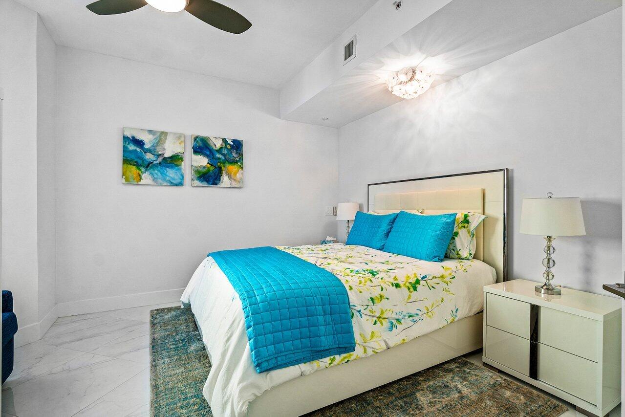 2640 Lake Shore Drive, Unit 2307 Riviera Beach, FL 33404 - Photo 30 of 64 a bedroom with a bed and a chandelier