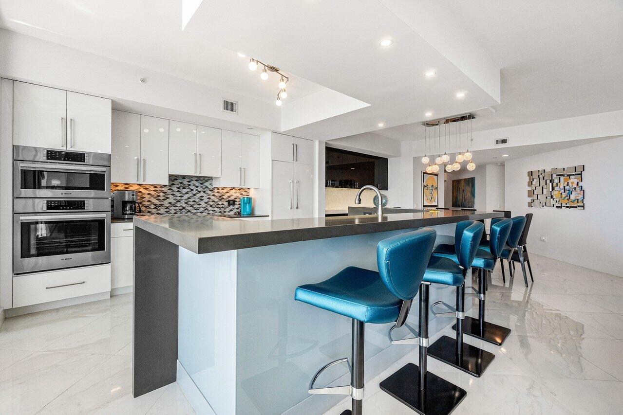 2640 Lake Shore Drive, Unit 2307 Riviera Beach, FL 33404 - Photo 6 of 64 a kitchen with stainless steel appliances kitchen island granite countertop a stove a sink a refrigerator and a microwave