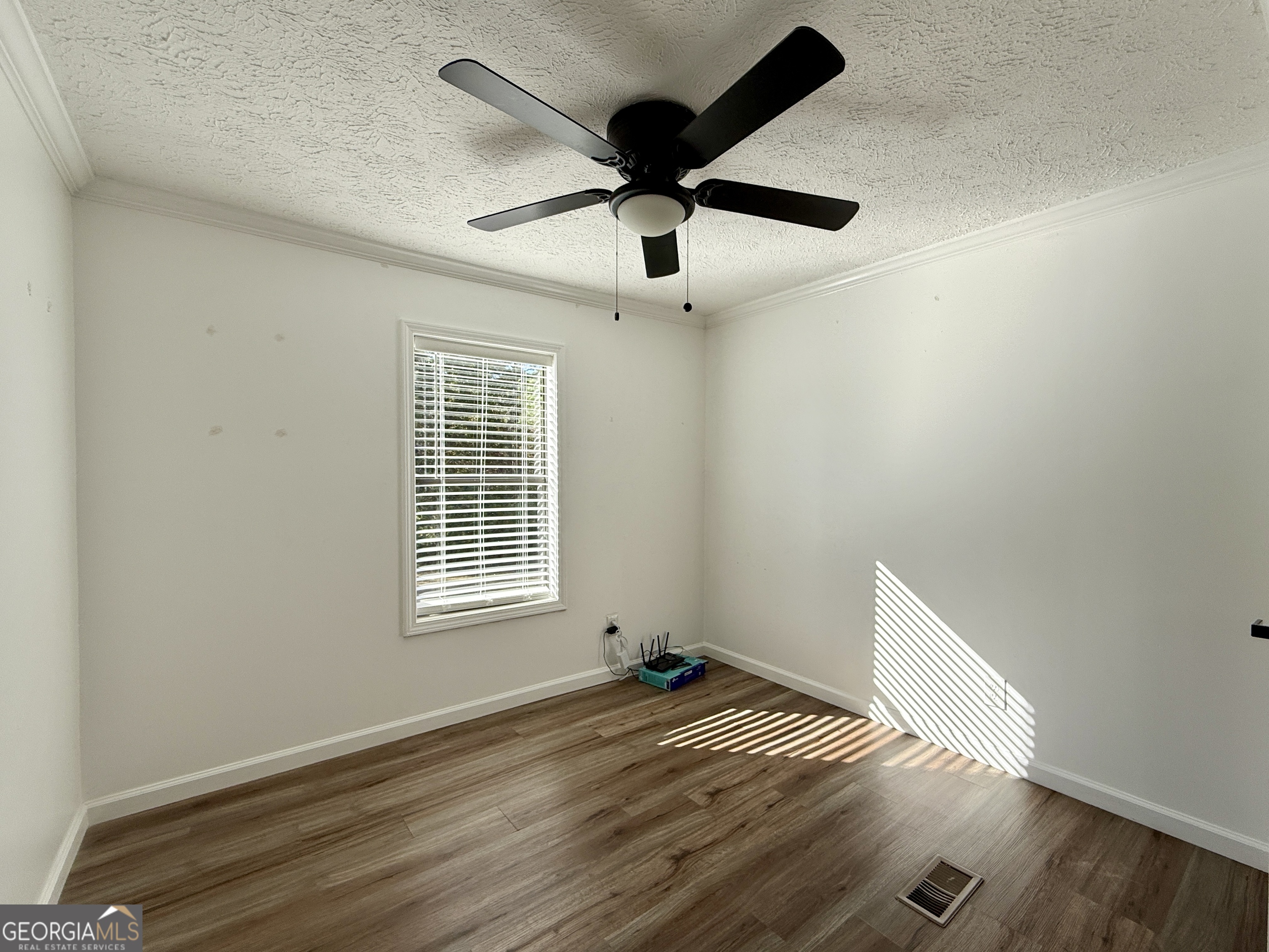 10199 Ga Highway Stapleton, GA 30823 - Photo 19 of 30 an empty room with wooden floor fan and windows