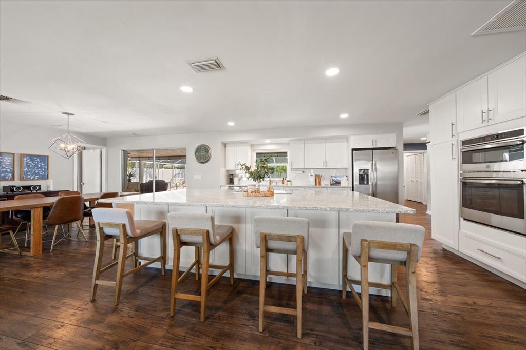1049 McCarty Street Dunedin, FL 34698 - Photo 3 of 49 a kitchen with stainless steel appliances kitchen island granite countertop a dining table chairs and granite counter tops
