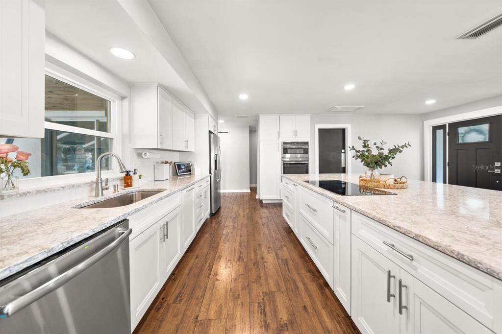 1049 McCarty Street Dunedin, FL 34698 - Photo 4 of 49 a large kitchen with stainless steel appliances kitchen island granite countertop a lot of counter space and wooden floors