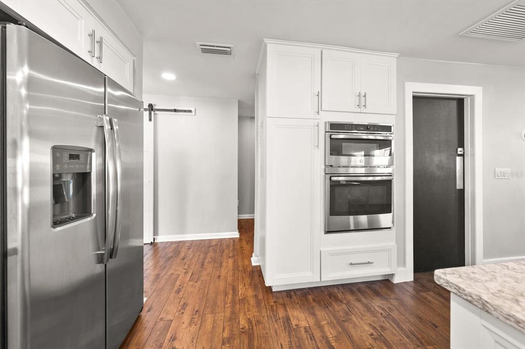 1049 McCarty Street Dunedin, FL 34698 - Photo 6 of 49 a kitchen with stainless steel appliances a refrigerator and wooden floor