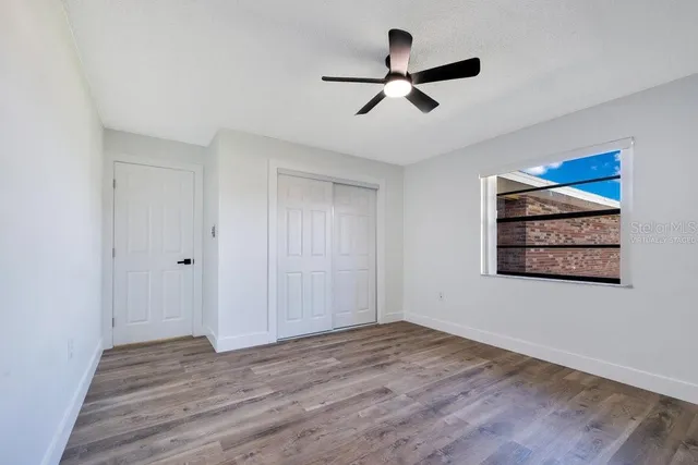 a view of a big room with wooden floor and windows