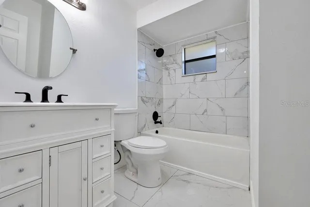 a bathroom with a toilet a sink a mirror and bathtub