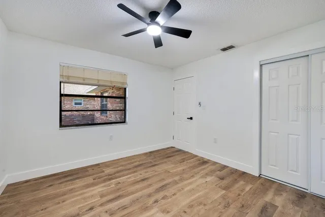 a view of an empty room with window and ceiling fan