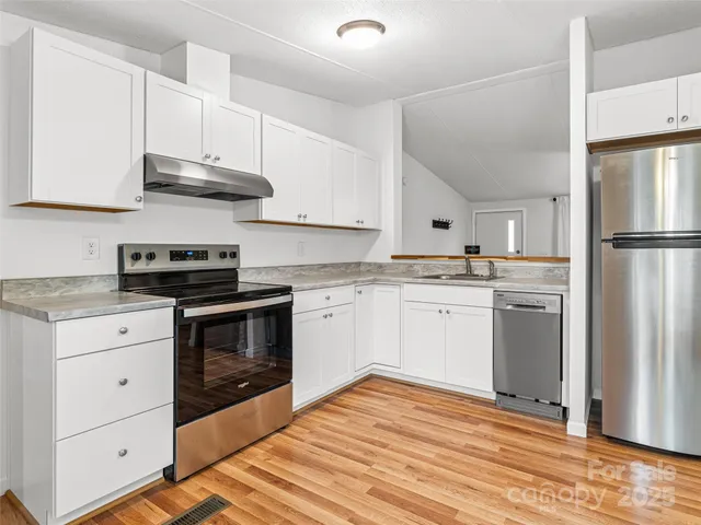 a kitchen with cabinets stainless steel appliances and wooden floor