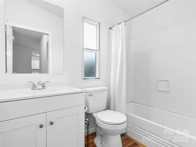 a bathroom with a toilet a sink a mirror a shower and vanity