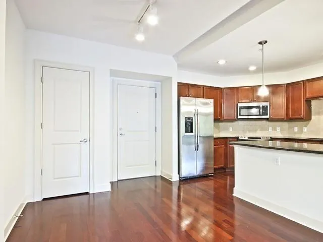 a large kitchen with stainless steel appliances granite countertop a stove a sink a refrigerator and a wooden floor