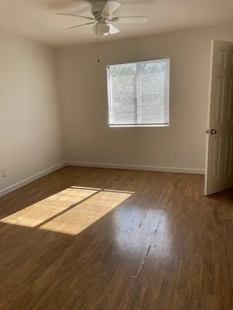 a view of empty room with wooden floor and fan