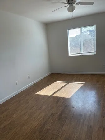 an empty room with wooden floor and windows