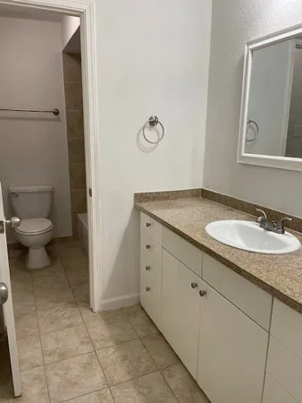 a bathroom with a granite countertop sink and a toilet