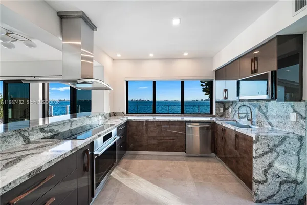 a large kitchen with granite countertop a sink and cabinets