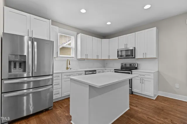 a kitchen with stainless steel appliances white cabinets and a refrigerator