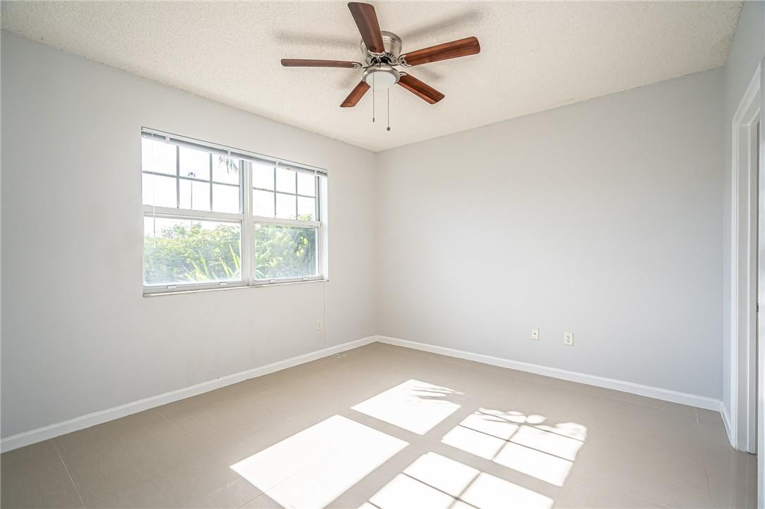 5860 West Sample Road, Unit 304 Coral Springs, FL 33067 - Photo 16 of 22 an empty room with a window and a ceiling fan