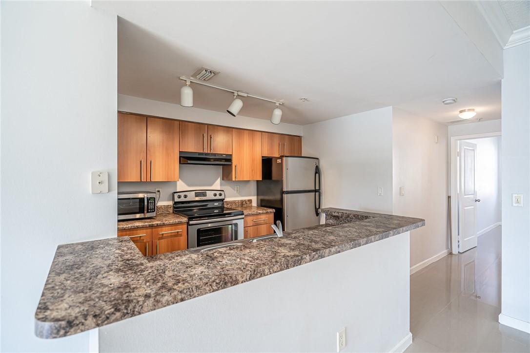 5860 West Sample Road, Unit 304 Coral Springs, FL 33067 - Photo 5 of 22 a kitchen with stainless steel appliances granite countertop a sink stove and refrigerator