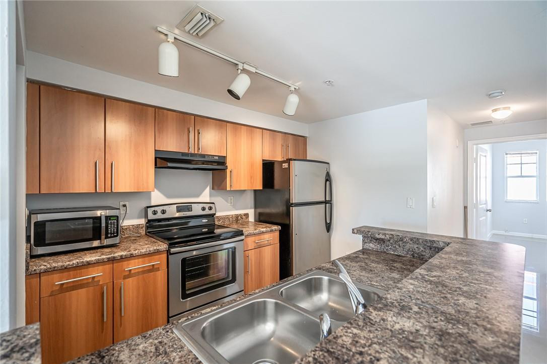 5860 West Sample Road, Unit 304 Coral Springs, FL 33067 - Photo 9 of 22 a kitchen with stainless steel appliances granite countertop a refrigerator a stove a sink and a microwave