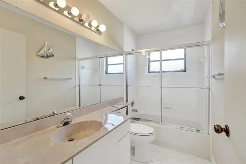 a bathroom with a granite countertop sink a toilet and shower