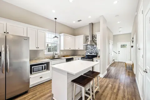 a large kitchen with kitchen island white cabinets and stainless steel appliances