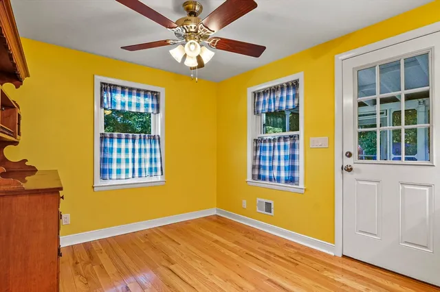 a view of an empty room with a window and chandelier fan