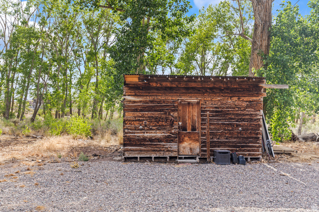 460 Omni Point Road Central Valley, UT 84754 - Photo 83 of 101 Rustic outbuilding with wood-plank siding and a wood door, surrounded by mature trees and a gravel ground cover