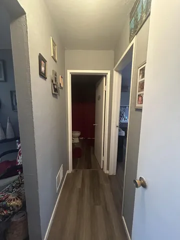 a view of a hallway with wooden floor and a bathroom