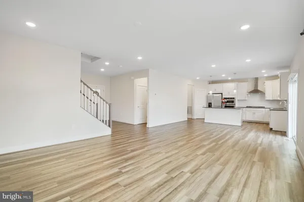 a kitchen with stainless steel appliances kitchen island granite countertop a refrigerator a sink a stove and white cabinets with wooden floor