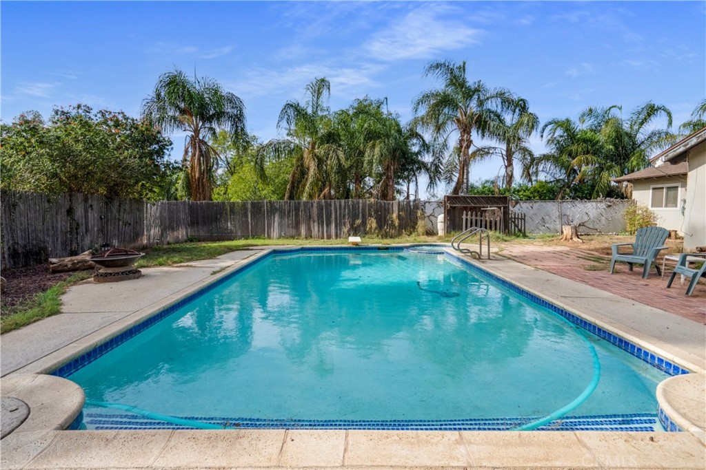 172 Eighth Street Norco, CA 92860 - Photo 26 of 55 a view of a swimming pool with a lawn chairs under palm trees
