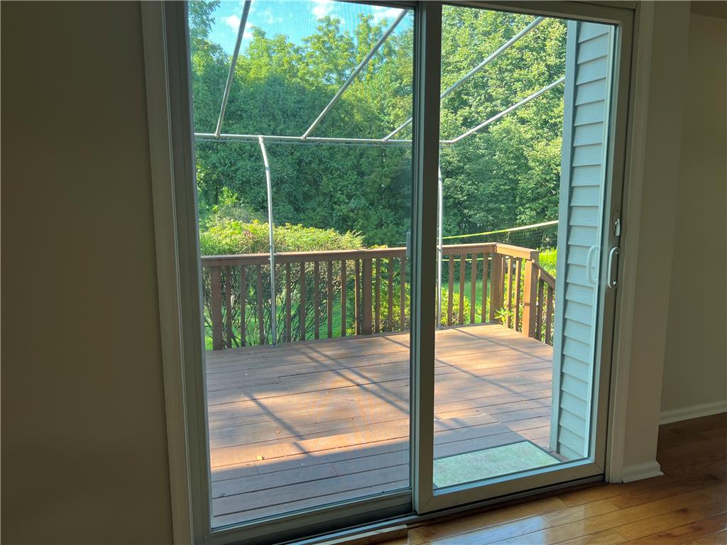 896 Briarstone Road Bethlehem, PA 18017 - Photo 16 of 37 Sliding glass doors open directly to a private wooden deck overlooking lush green trees.