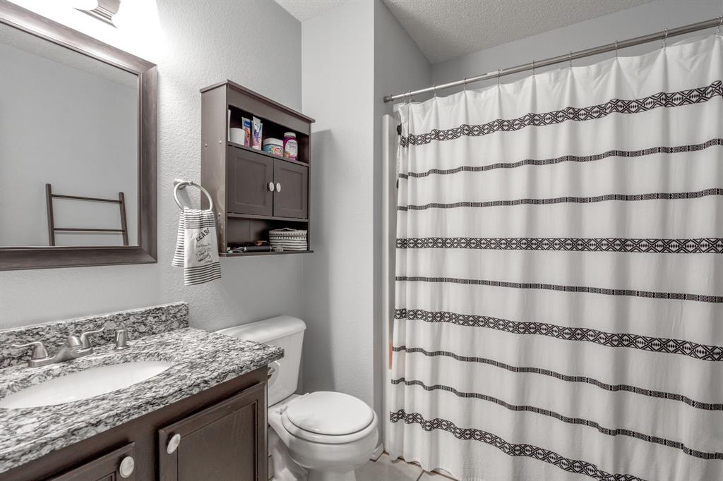 1973 Lariat Drive Fort Worth, TX 76247 - Photo 14 of 28 a bathroom with a granite countertop sink toilet and shower
