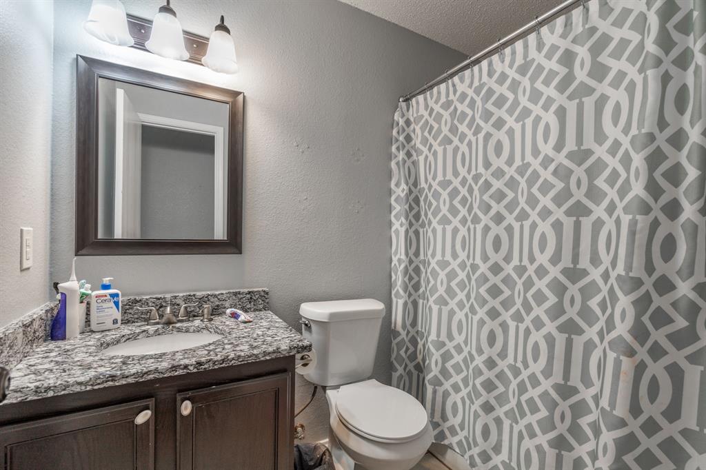1973 Lariat Drive Fort Worth, TX 76247 - Photo 17 of 28 a bathroom with a granite countertop toilet sink and mirror