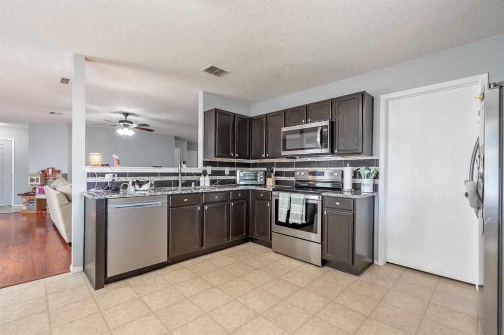 1973 Lariat Drive Fort Worth, TX 76247 - Photo 28 of 28 a kitchen with stainless steel appliances granite countertop a stove top oven a refrigerator and a sink