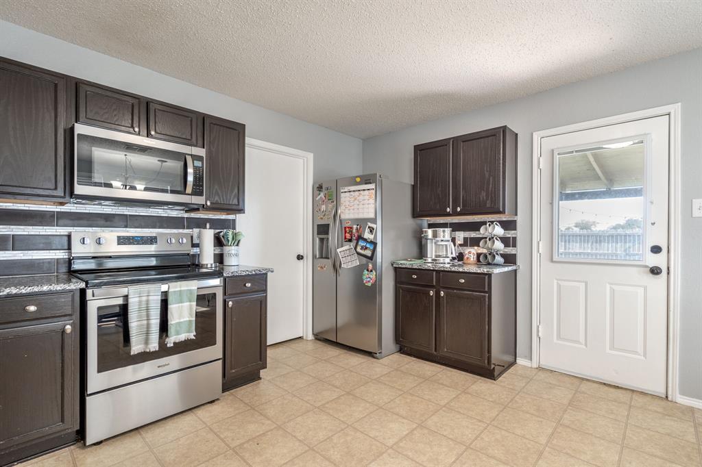 1973 Lariat Drive Fort Worth, TX 76247 - Photo 9 of 28 a kitchen with stainless steel appliances granite countertop a stove and a refrigerator