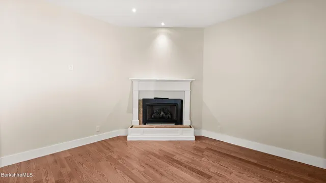 a view of an empty room with wooden floor and a fireplace