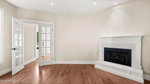 a view of an empty room with wooden floor fireplace and a window