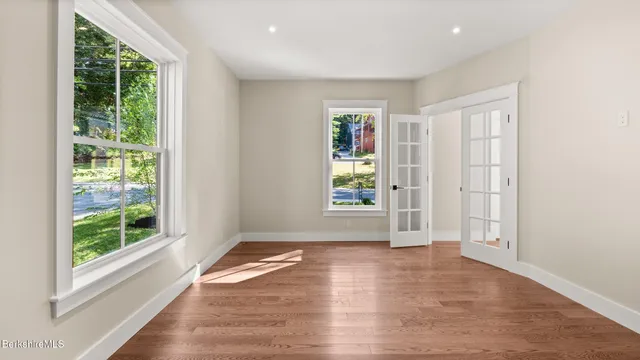 an empty room with wooden floor and windows