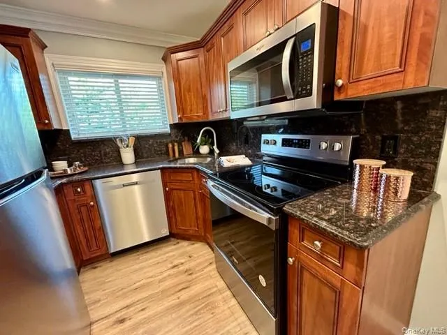 a kitchen with granite countertop cabinets stainless steel appliances a sink and a window