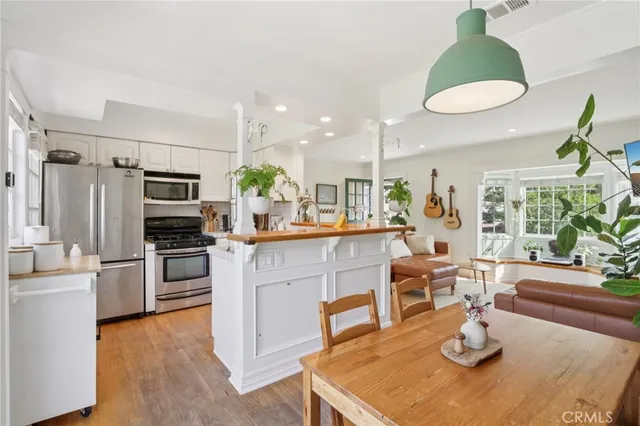 a kitchen with stainless steel appliances kitchen island granite countertop a refrigerator a stove a sink dishwasher a dining table and chairs with wooden floor