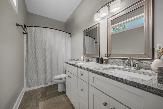a bathroom with a granite countertop sink a toilet and a mirror