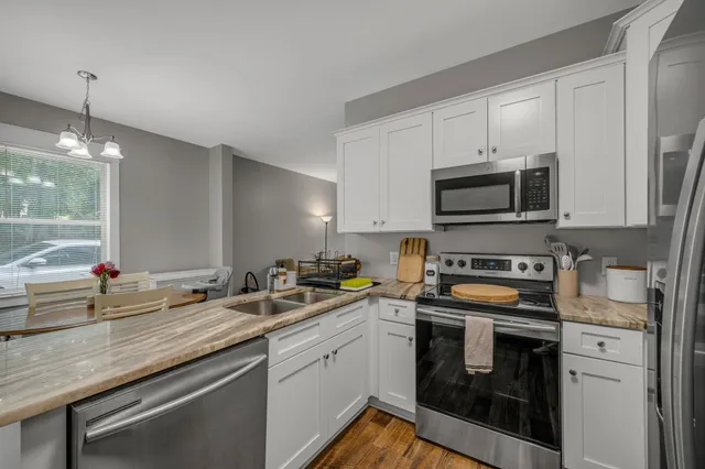 a kitchen with stainless steel appliances white cabinets a sink and a stove