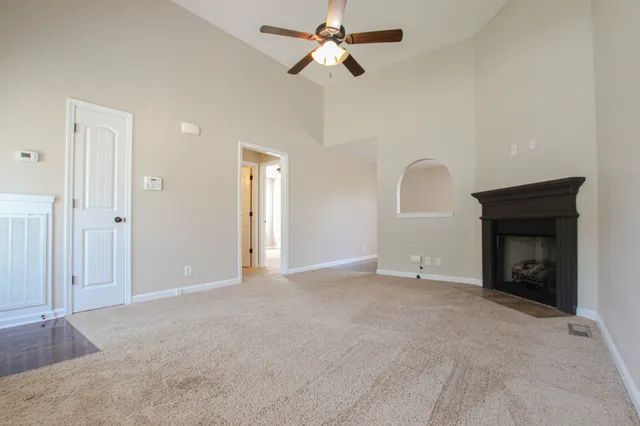 an empty room with a fireplace and a ceiling fan