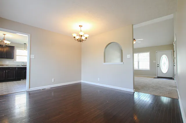 an empty room with wooden floor mirror and windows