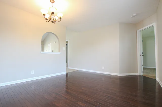 an empty room with wooden floor and chandelier