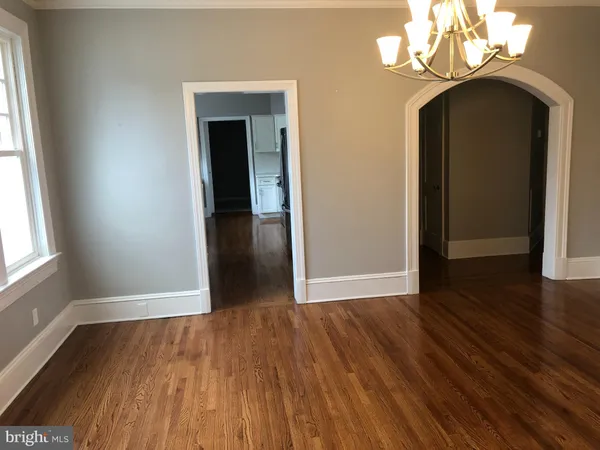 an empty room with wooden floor cabinet and windows