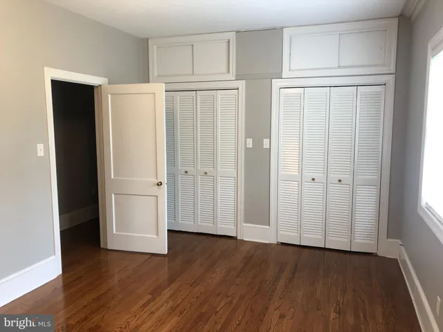 an empty room with wooden floor and closet area