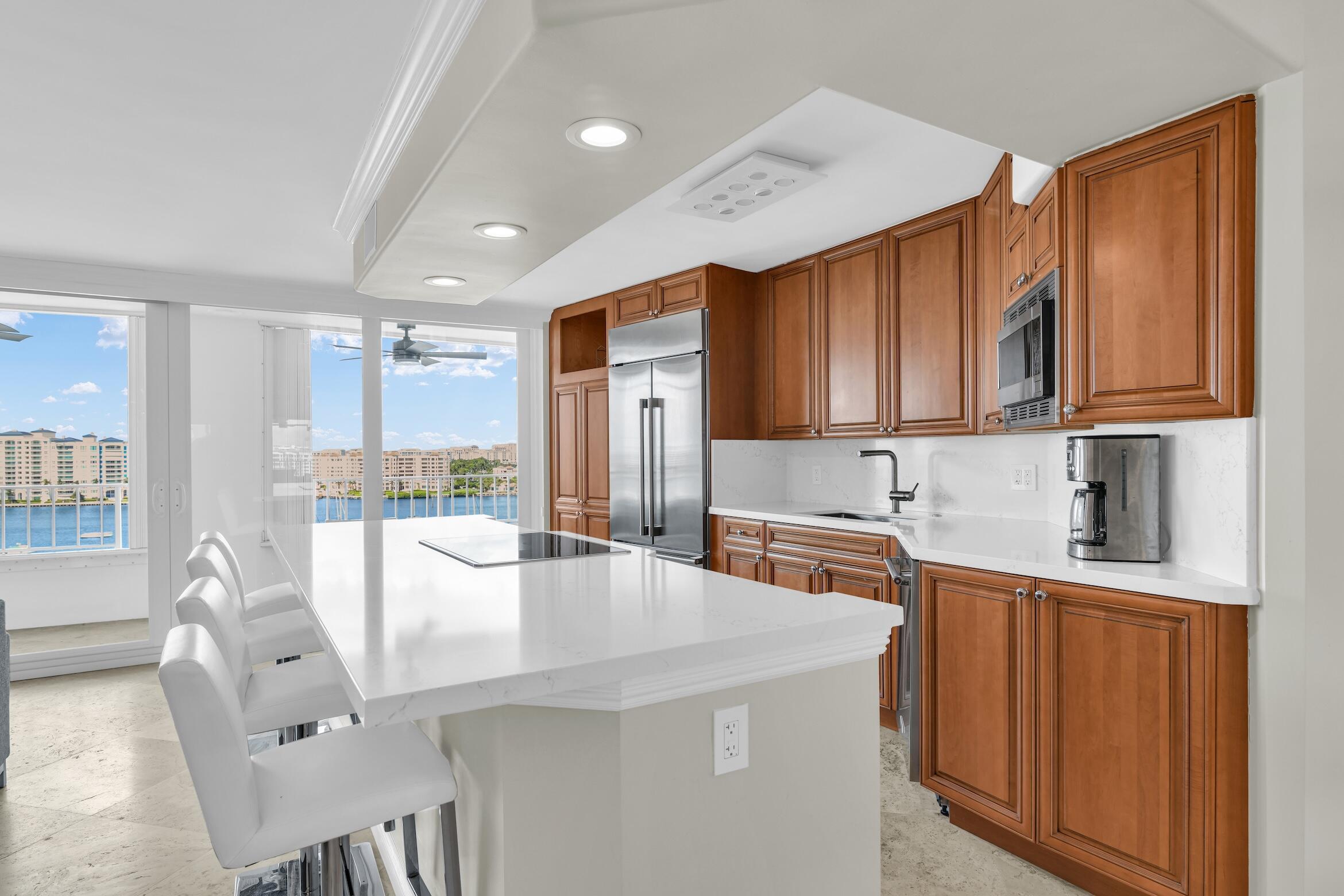 500 South Ocean Boulevard, Unit 1009 Boca Raton, FL 33432 - Photo 5 of 57 a kitchen with stainless steel appliances granite countertop a refrigerator a sink dishwasher a stove with wooden cabinets and floor