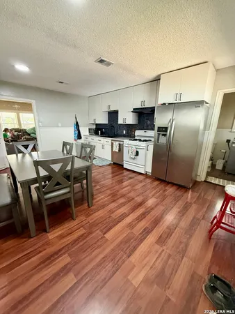 a kitchen with stainless steel appliances wooden floor and a refrigerator