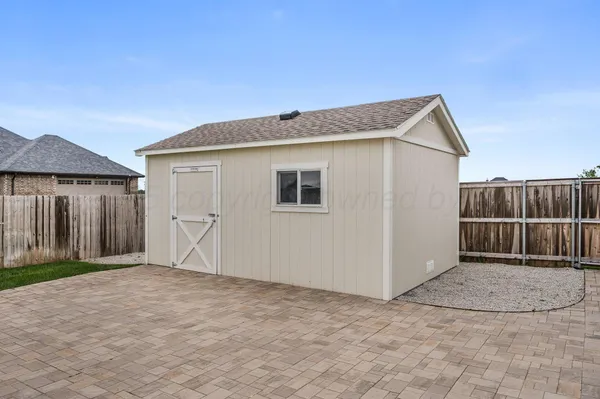 a view of backyard with small cabin and wooden fence