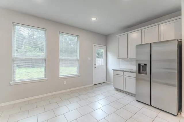 a kitchen with white cabinets and refrigerator
