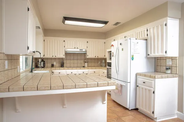 a kitchen with a refrigerator a stove a sink and white cabinets